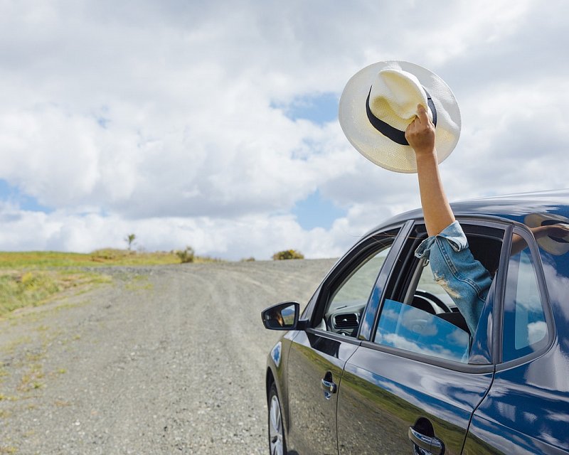  Person wearing a hat enjoys a scenic car ride.